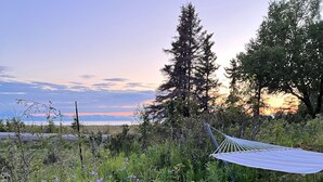 A hammock in a garden with purple flowers and a mountain in the background. - Gorgeous Modern Alaskan Home with Ocean /Mt View 10 minute walk to sandy beach (Kenai)