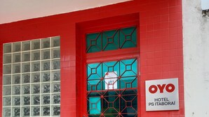 A red building with a glass door and windows, a sign reading "OYO HOTEL PS ITABORAÍ", and a small entrance with steps. - Ps Hotel Manilha (Itaborai)