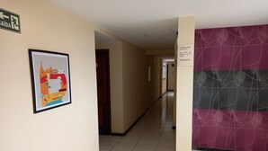 A hotel corridor with a framed picture on the left, a purple wall on the right, and a sign indicating a smoking area. - Ps Hotel Manilha (Itaborai)