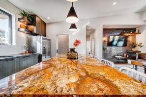 A modern kitchen with a large island, stainless steel appliances, and a stone backsplash. - LaFave-Luxury Villa at Zion: Mountain of the Sun (Springdale)