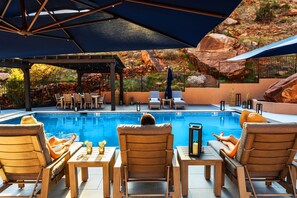 A poolside area with lounge chairs, a covered seating area, and a view of rocky terrain. - LaFave-Luxury Villa at Zion: Mountain of the Sun (Springdale)