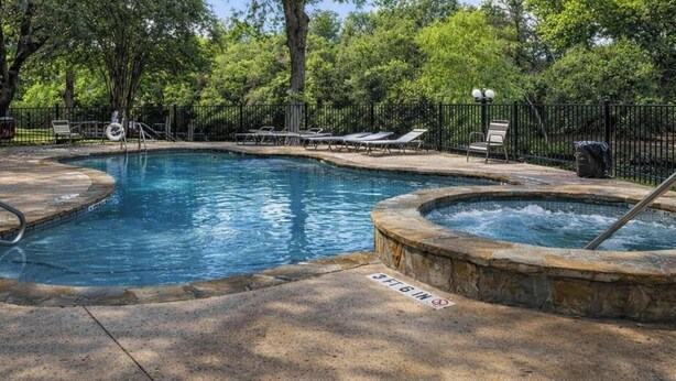 Una piscina con lettini e una vasca idromassaggio.