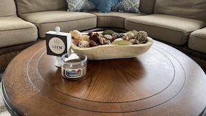 Una mesa de centro redonda de madera con una vela y un cuenco decorativo encima.