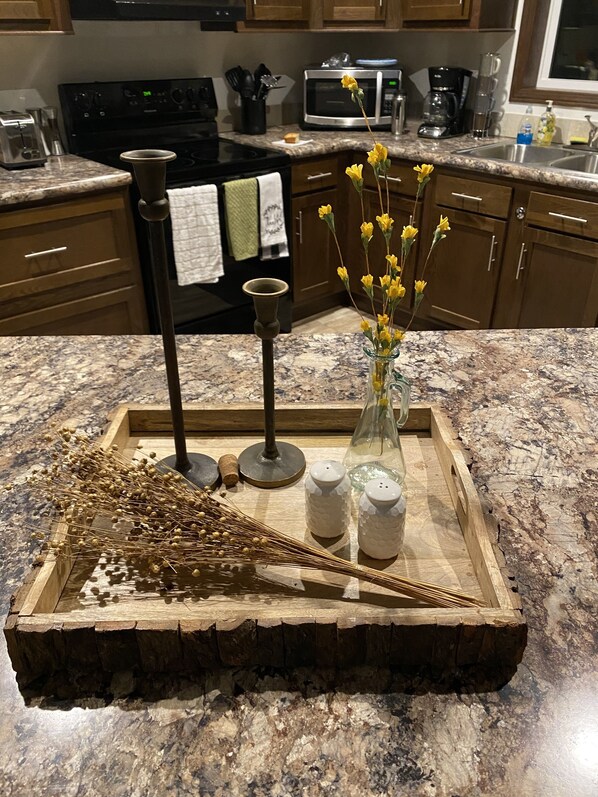 A kitchen counter with a decorative tray holding a vase of yellow flowers, salt and pepper shakers, and a candle holder.