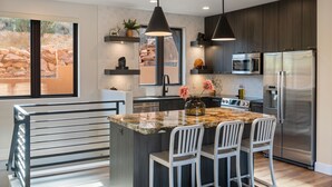 A modern kitchen with a central island, stainless steel appliances, and pendant lighting.