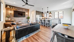 A modern living room with a fireplace, leather sofa, and dining area with a wooden table and chairs.