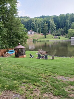 A serene lakeside setting with a gazebo, outdoor seating, and a house in the background. - Hideaway On The Lake. (Guntersville)