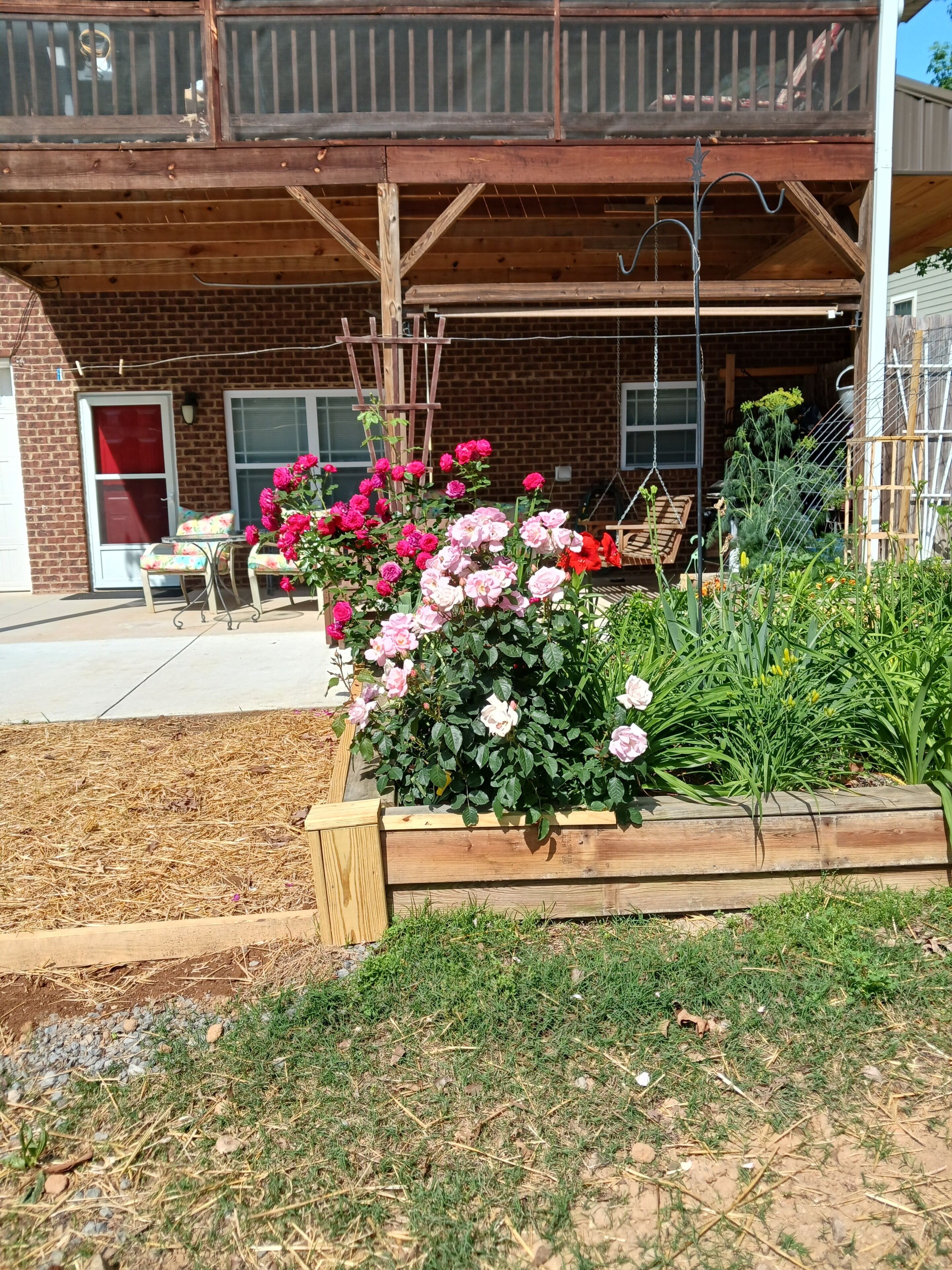 A patio area with a wooden deck, a brick wall, and a small table with chairs.