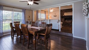Un coin repas avec une table et des chaises en bois, un ventilateur de plafond et une cheminée en briques.