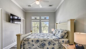 Ein Schlafzimmer mit einem Bett, einem Nachttisch, einer Lampe und einem Deckenventilator.