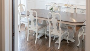 Un espace repas comprenant une table rectangulaire, des chaises blanches et un lustre doté de plusieurs points lumineux.