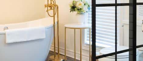 Une salle de bain avec une baignoire, des toilettes et une petite table sur laquelle est posé un vase de fleurs.