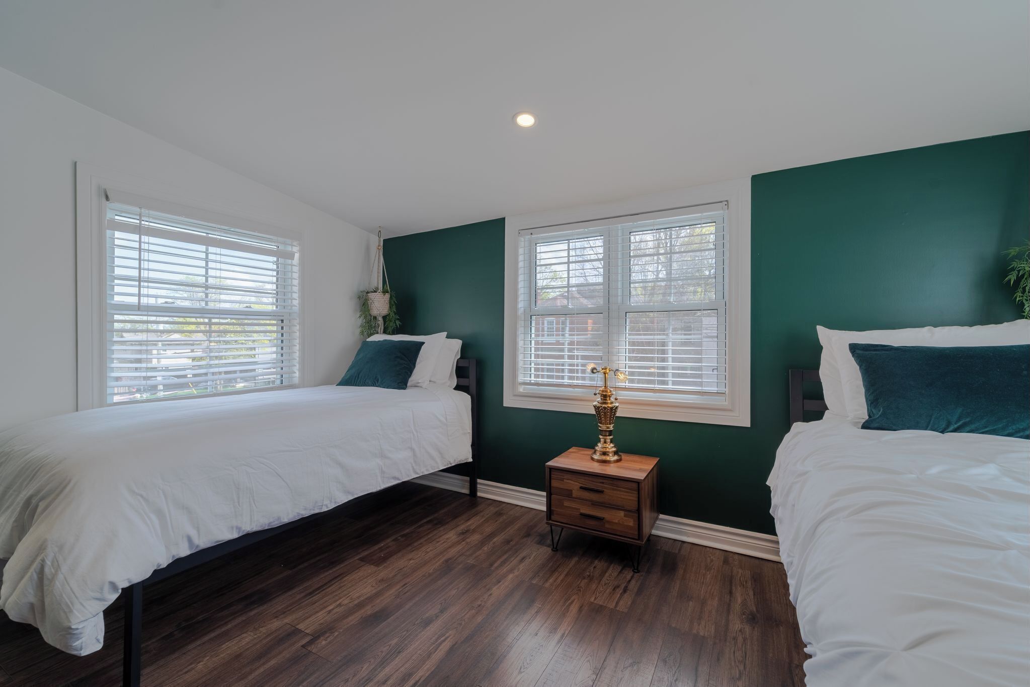 A bedroom with two beds, a nightstand, and a window with blinds.