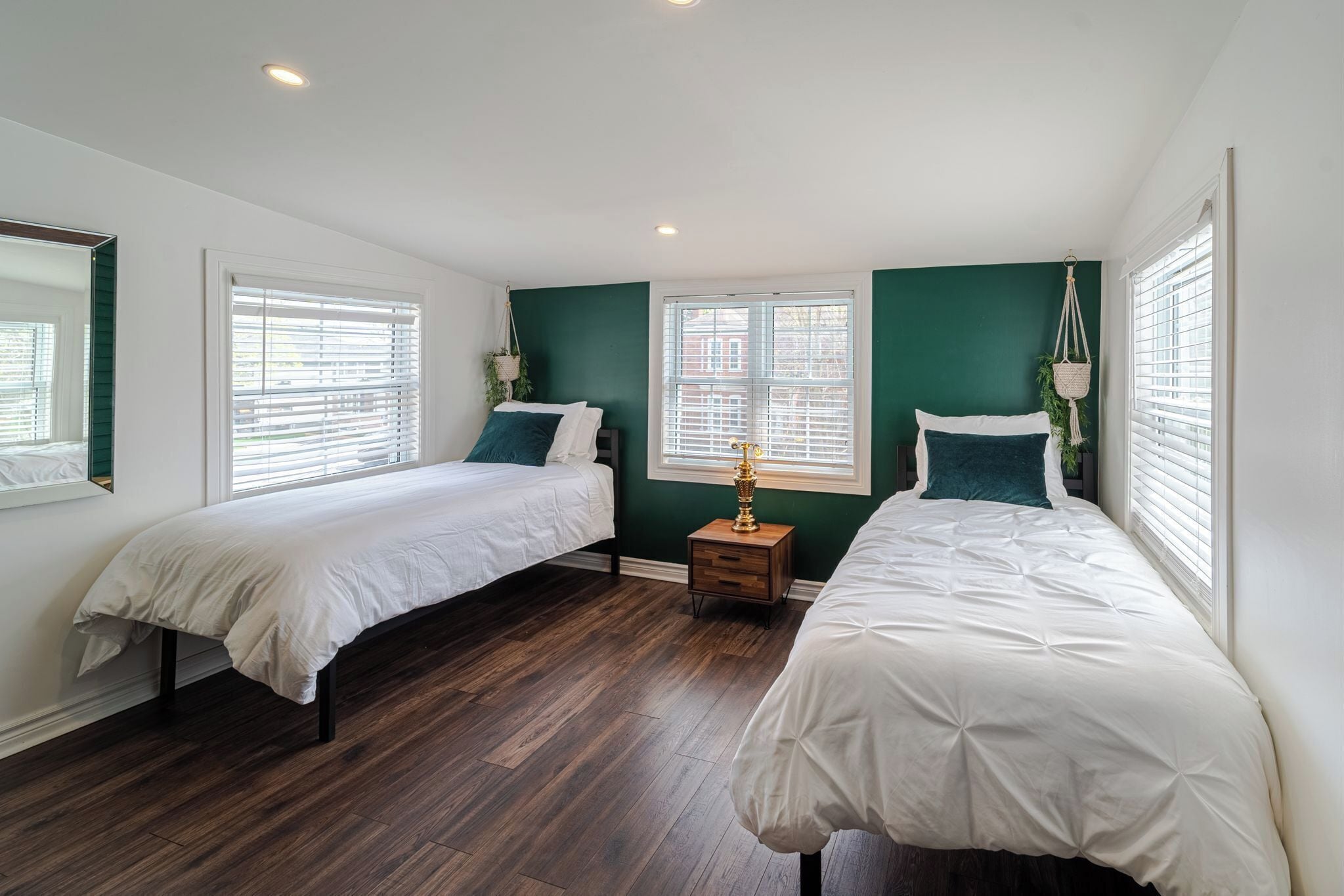 A bedroom with two beds, a nightstand, and a window with blinds.