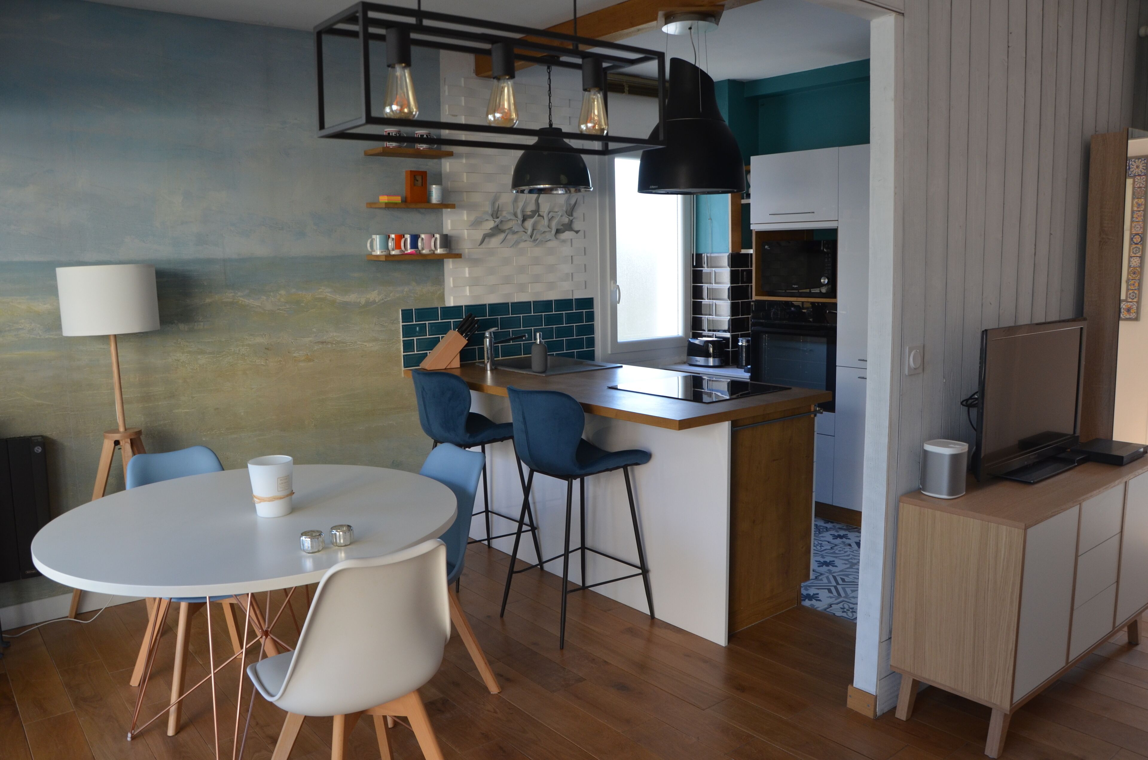 Una cocina moderna con una isla central, taburetes de bar e iluminación colgante.