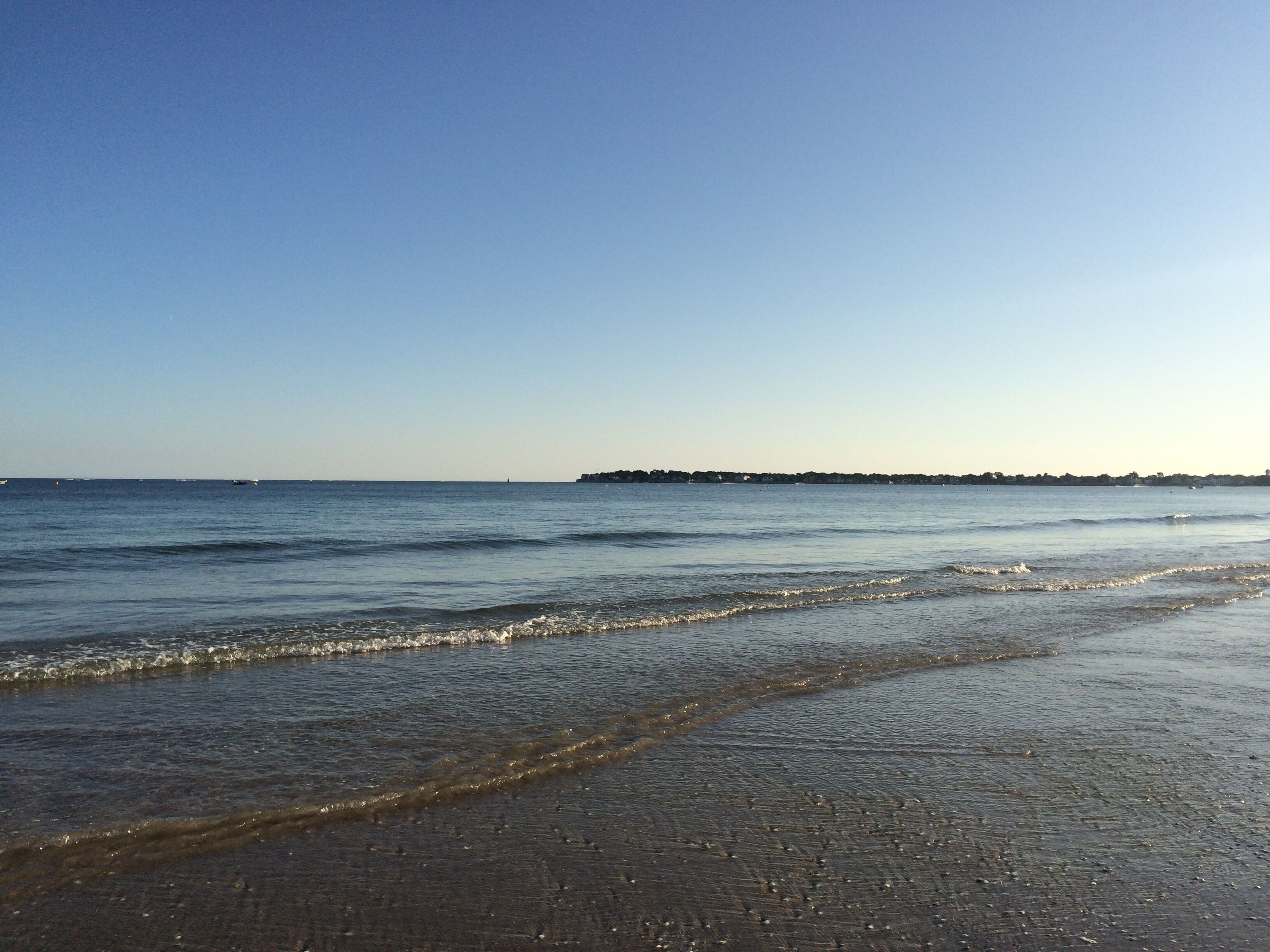 A beach with calm waters and a distant shoreline.