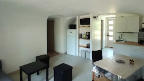 Ein kompakter Wohnraum mit Küchenzeile, Essbereich und einer kleinen Sitzecke.