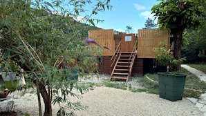 Eine Holzhütte mit einer Treppe, die zu einer Tür führt, umgeben von Kies und Topfpflanzen.