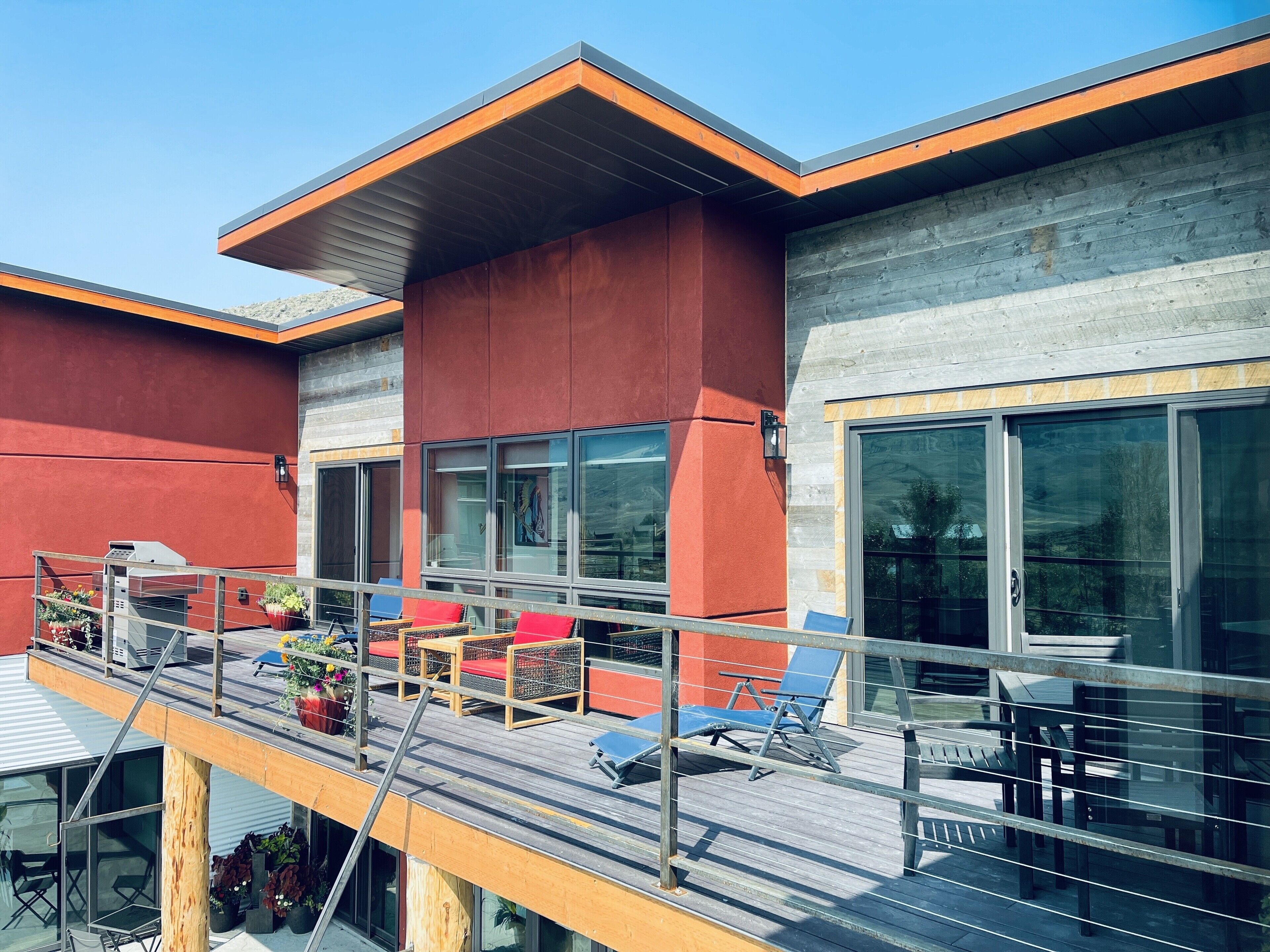 A modern building with a balcony, large windows, and outdoor seating.