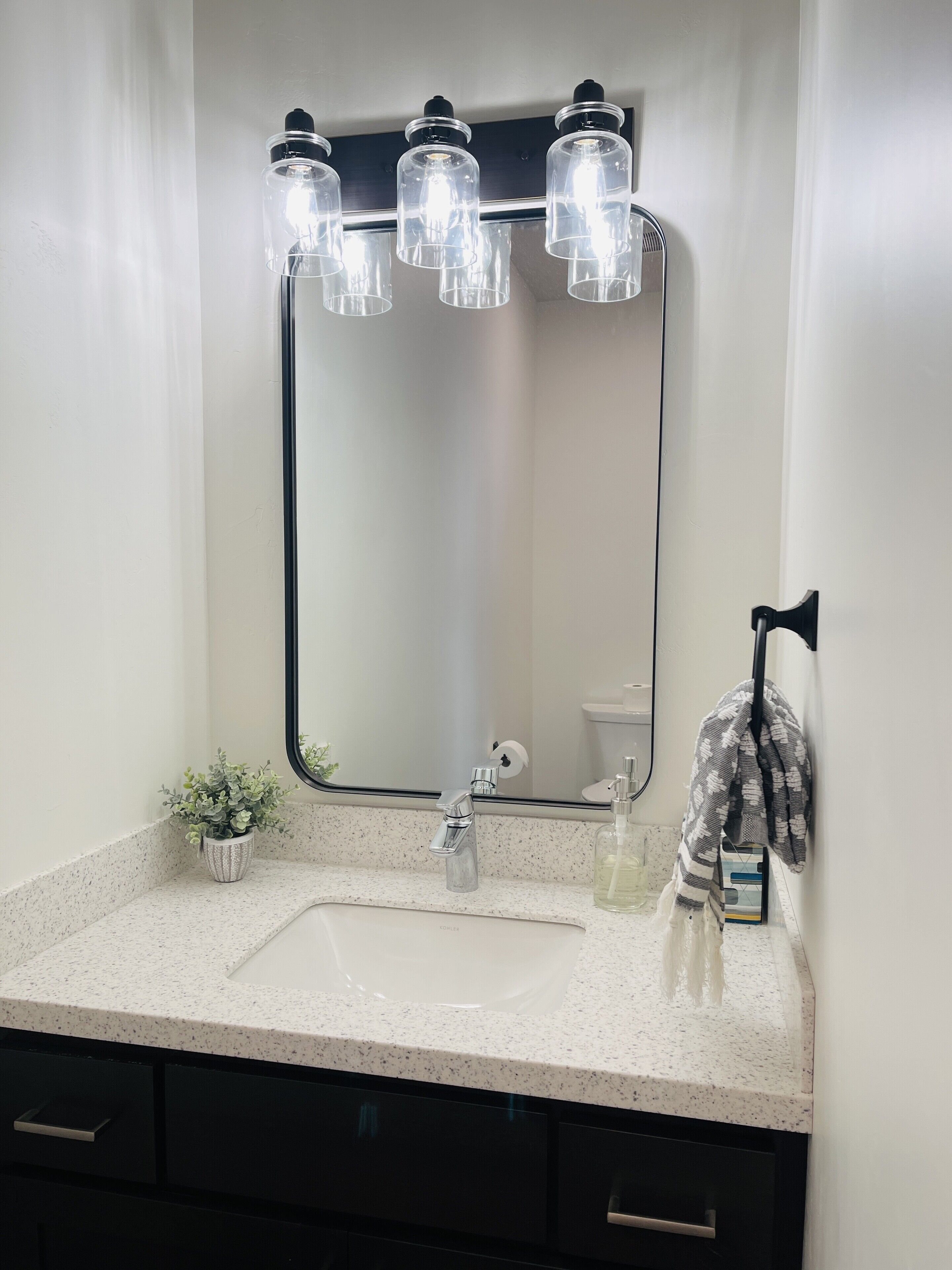 A bathroom with a white sink, a mirror, and a towel rack.