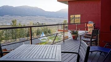 A wooden deck with a table and chairs, overlooking a mountainous landscape.