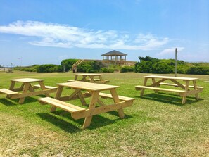 Ein Picknickbereich mit Holztischen und -bänken, einem Pavillon und einer Rasenfläche.
