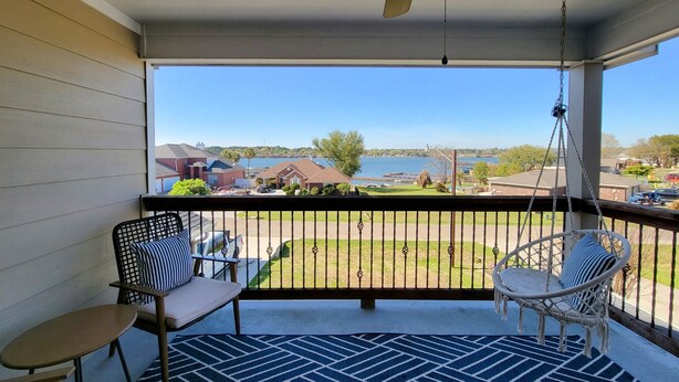 A covered porch with a ceiling fan, two chairs, a small table, and a patterned rug.