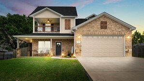 A two-story house with a front porch, a garage, and a well-maintained lawn.