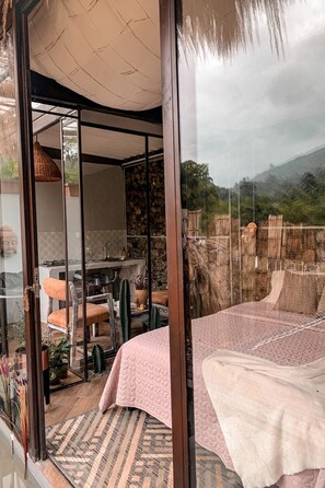 Relax in this serene room with an outdoor access, a comfortable bed, and a wicker lamp.