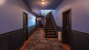 Un couloir doté d’un sol recouvert de moquette, d’un escalier et de portes de part et d’autre.