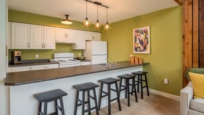 A modern kitchen with white cabinets, a central island with stools, and pendant lighting.