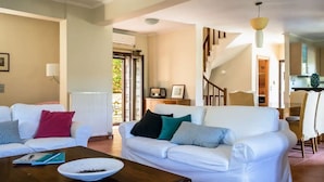 A living room with a white sofa, a coffee table, and a staircase leading to another room. - Luxurious Pool Villa Kavalos (6-11people) (Kavallos)