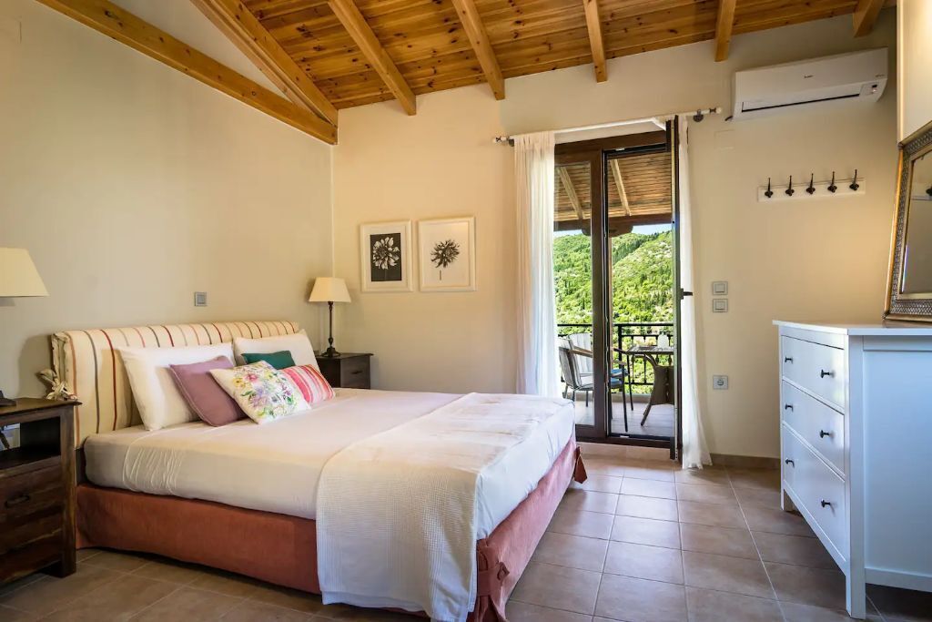 A bedroom with a bed, bedside tables, a dresser, and a view of the outdoors.