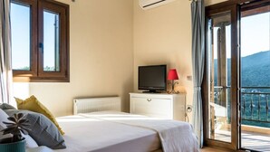A bedroom with a bed, a television, a radiator, and a balcony with a view of the mountains. - Luxurious Pool Villa Kavalos (6-11people) (Kavallos)