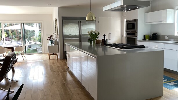 A modern kitchen with a large island, stainless steel appliances, and a dining area with a view of the outdoors. - Ultimate Summer Vacation Home (Los Angeles)