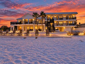 A beachfront property with a two-story building, outdoor seating, and a staircase leading to the upper level.