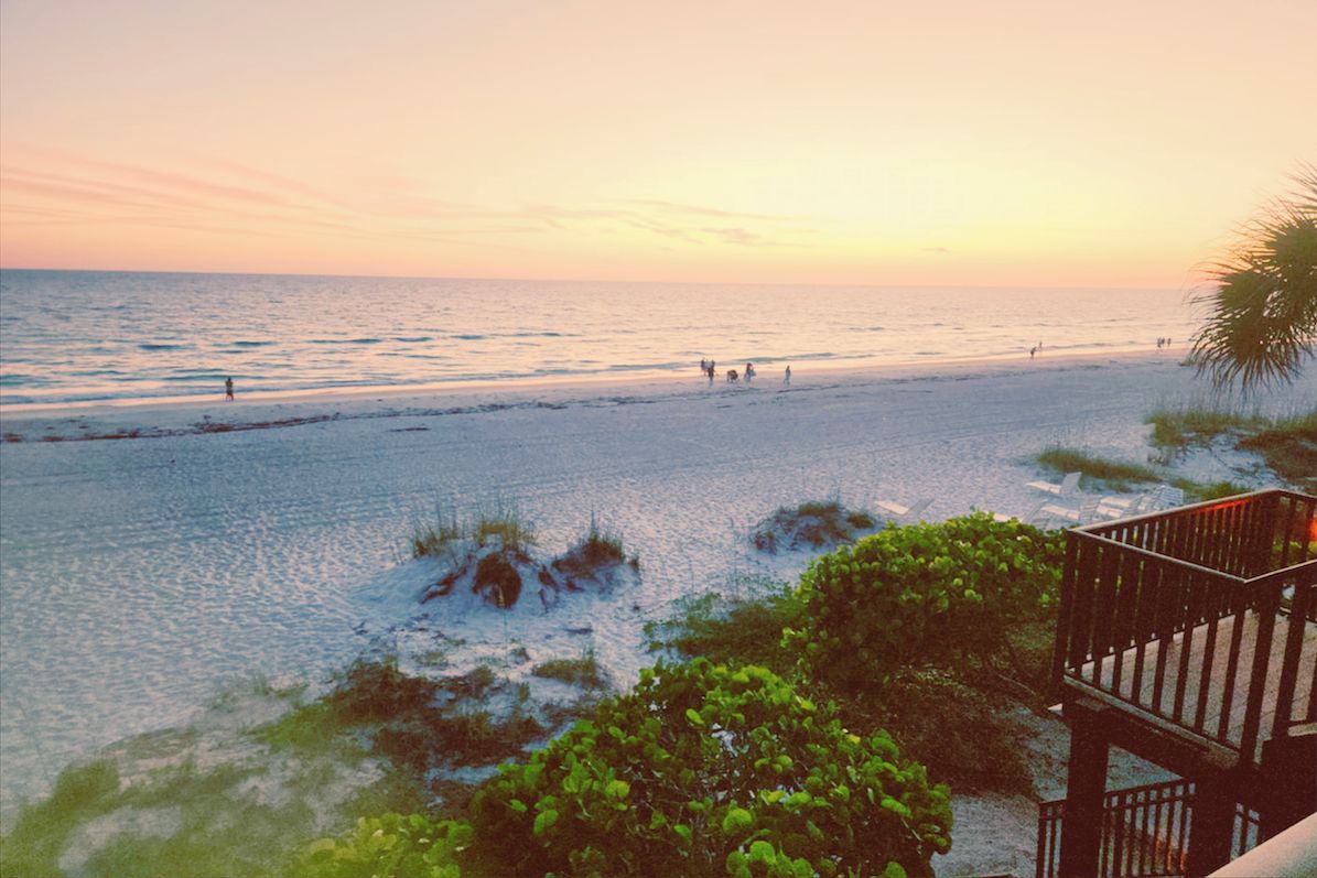 A beach with a wooden deck overlooking the ocean.