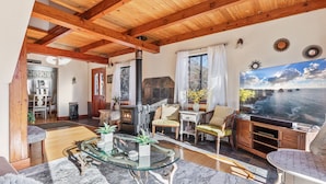 Un salón amplio con una mesa de centro de cristal, muebles de madera, una chimenea y una gran pantalla de televisión que muestra una vista panorámica.