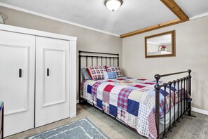 A bedroom with a bed, a wardrobe, a mirror, and a carpet.