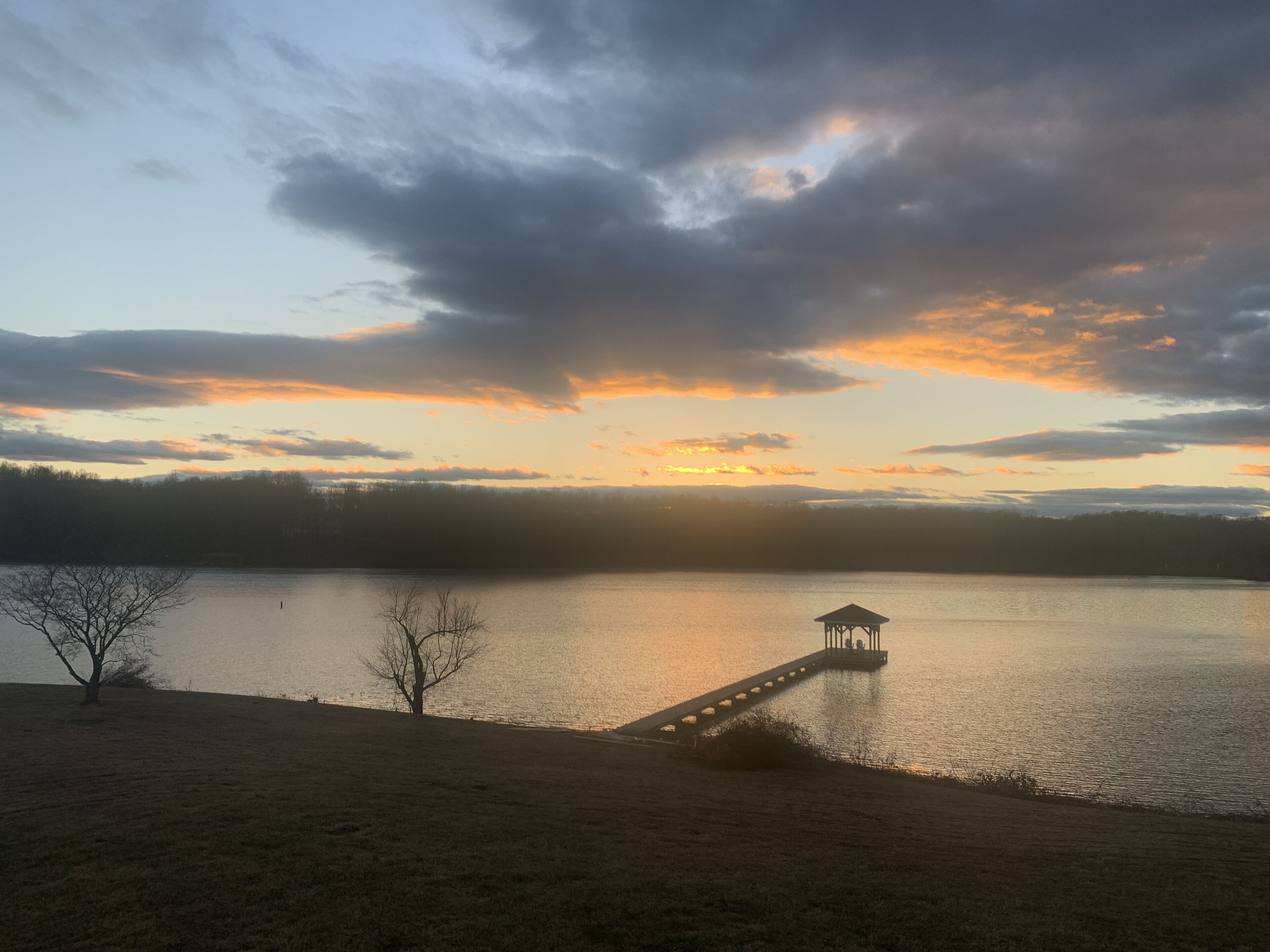A lakeside view with a gazebo on a dock extending into the water.