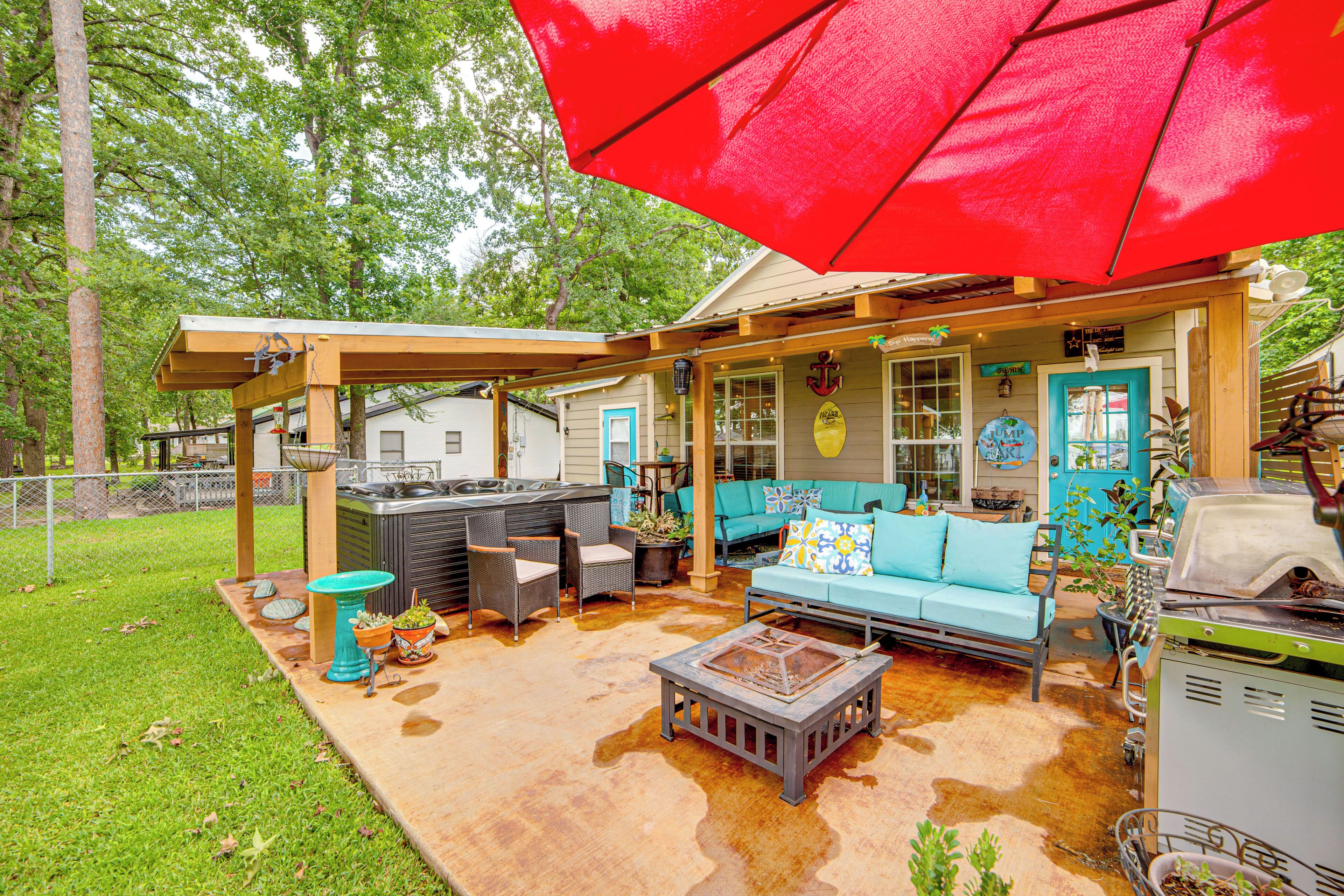 An outdoor patio area with a barbecue grill, a blue sofa, and a red umbrella.