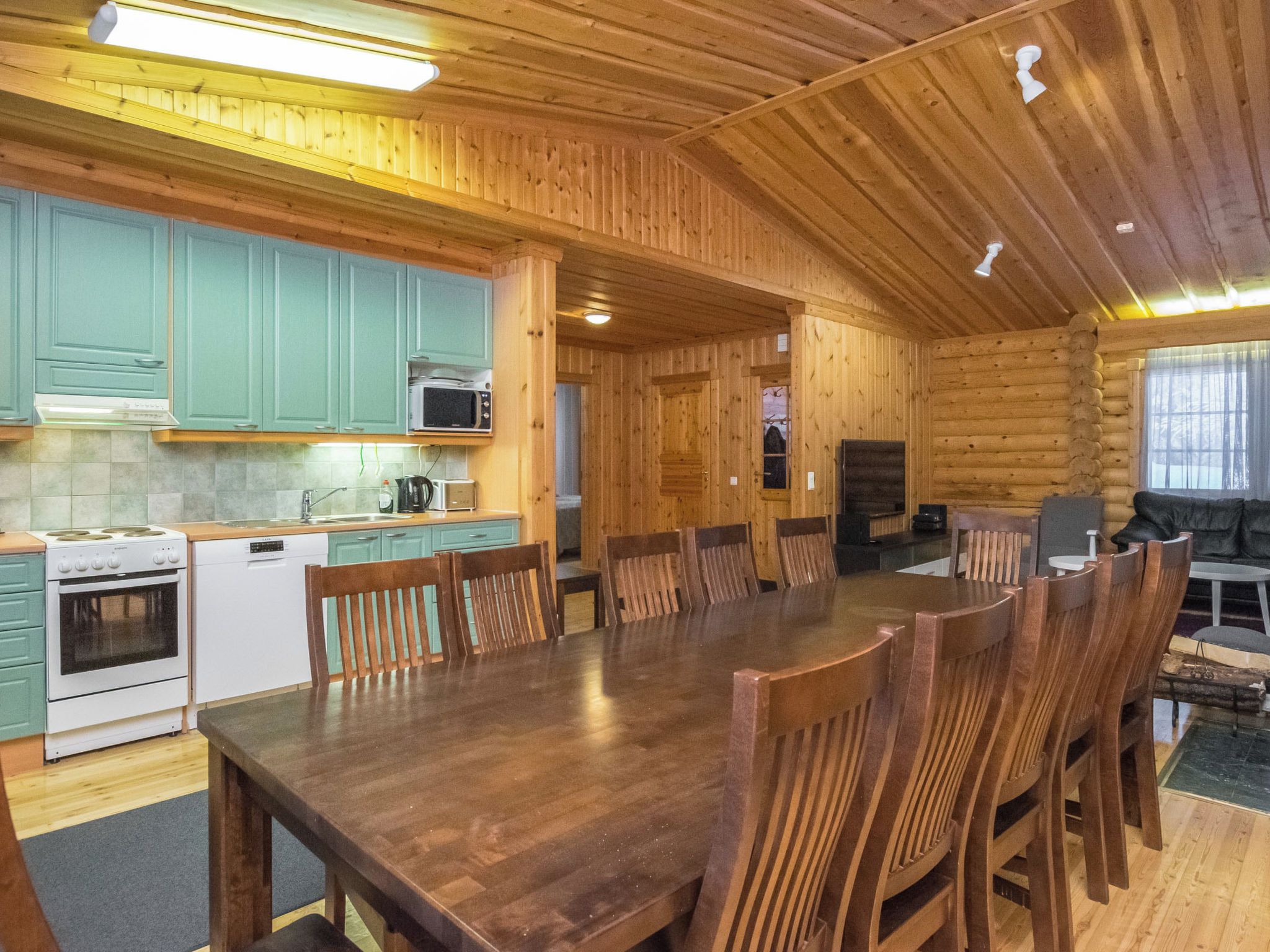 L’intérieur d’un chalet en bois comprend une cuisine, une table à manger et un coin salon.