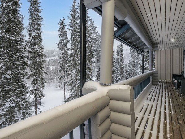 A snow-covered balcony with a view of snow-laden trees and a clear sky.