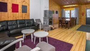 A cozy cabin interior with a leather sofa, a stone fireplace, and a dining area.