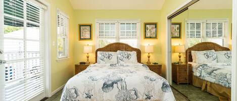 A bedroom with a bed, two bedside tables, two lamps, a mirror, and a window with blinds.