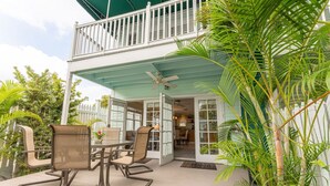 A covered patio with outdoor furniture, a ceiling fan, and a white fence. - Roosters Perch at Truman Annex- LOW SUMMER RATES!!! (Key West)