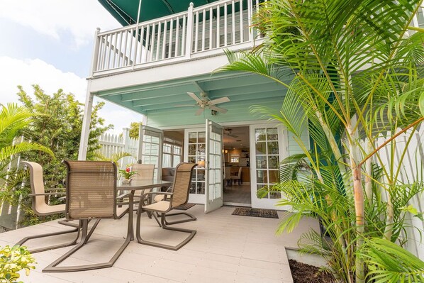 A covered patio with outdoor furniture, a ceiling fan, and a white fence. - Roosters Perch at Truman Annex- LOW SUMMER RATES!!! (Key West)