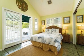 A bedroom with a bed, two nightstands, and a window with blinds. - Roosters Perch at Truman Annex- LOW SUMMER RATES!!! (Key West)