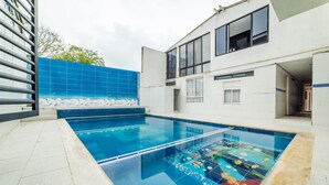 Una piscina con un borde de baldosas y un edificio moderno al fondo.