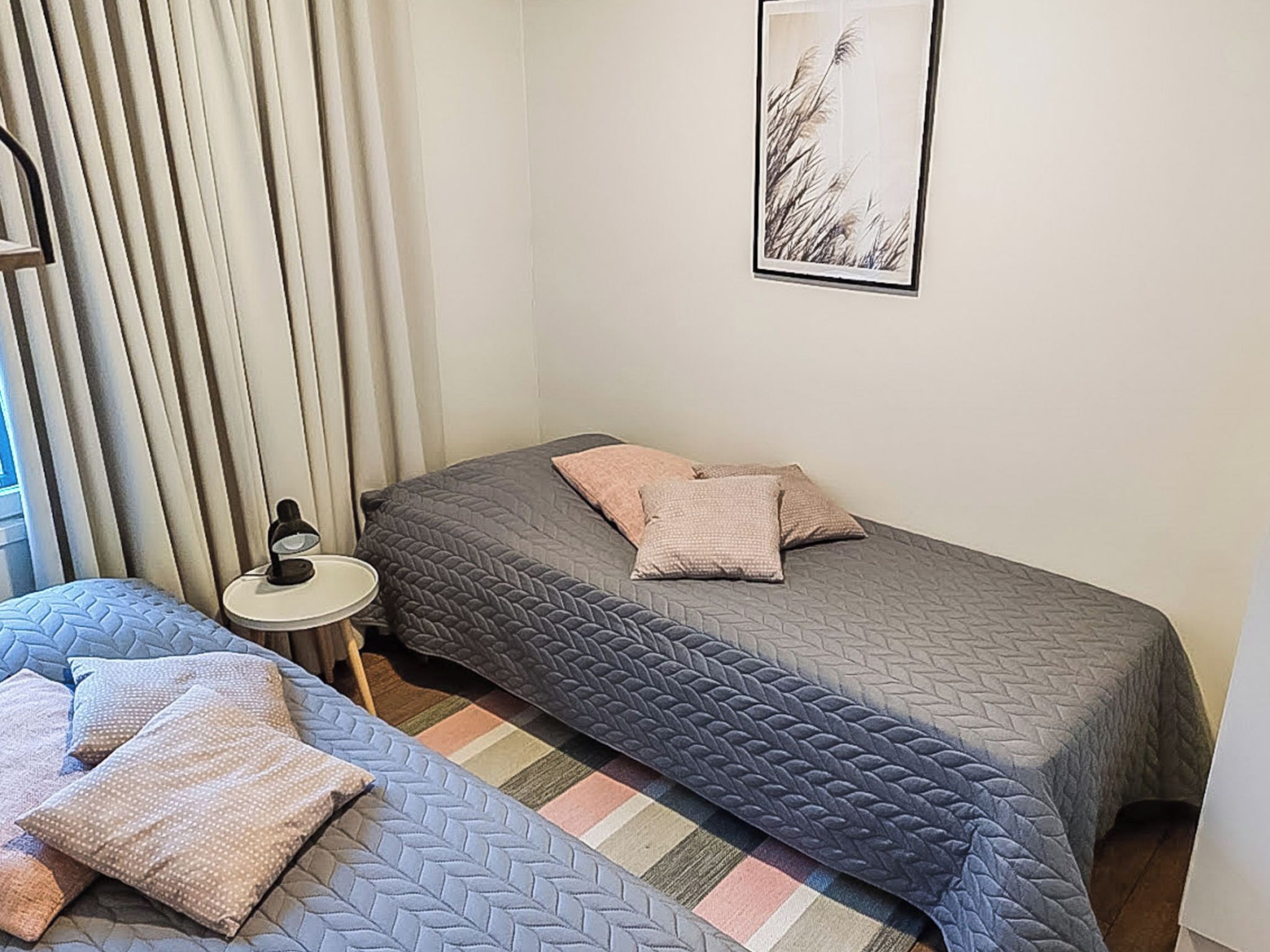 A bedroom with two beds, a bedside table, a lamp, and a framed picture on the wall.